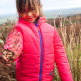 Child wearing the Frugi reversible toasty trail jacket in pretty paisley showing the pink reverse side and purple front zip