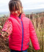 Child wearing the Frugi reversible toasty trail jacket in pretty paisley showing the pink reverse side and purple front zip