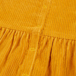 A closer look at the popper fasteners on the back of the Frugi Lovely Lily Cord Dress - Gold/Red Panda