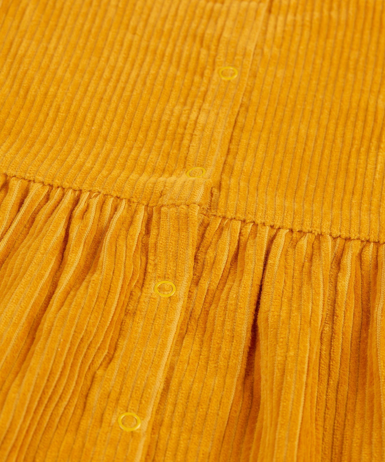 A closer look at the popper fasteners on the back of the Frugi Lovely Lily Cord Dress - Gold/Red Panda