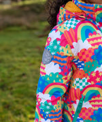 Child wearing the Frugi snow and ski coat in the fun frenzy design showing a close up of a brand patch on the upper arm