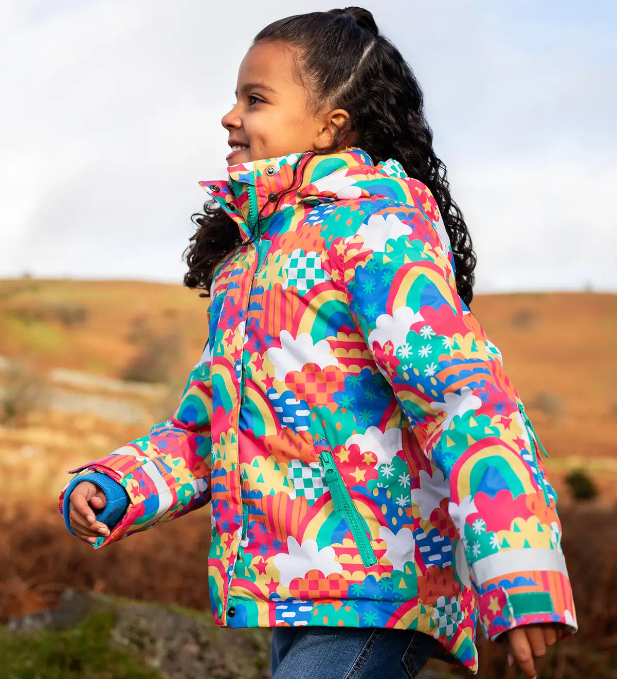 Child wearing the Frugi snow and ski coat in the fun frenzy design showing a zipped side pocket 