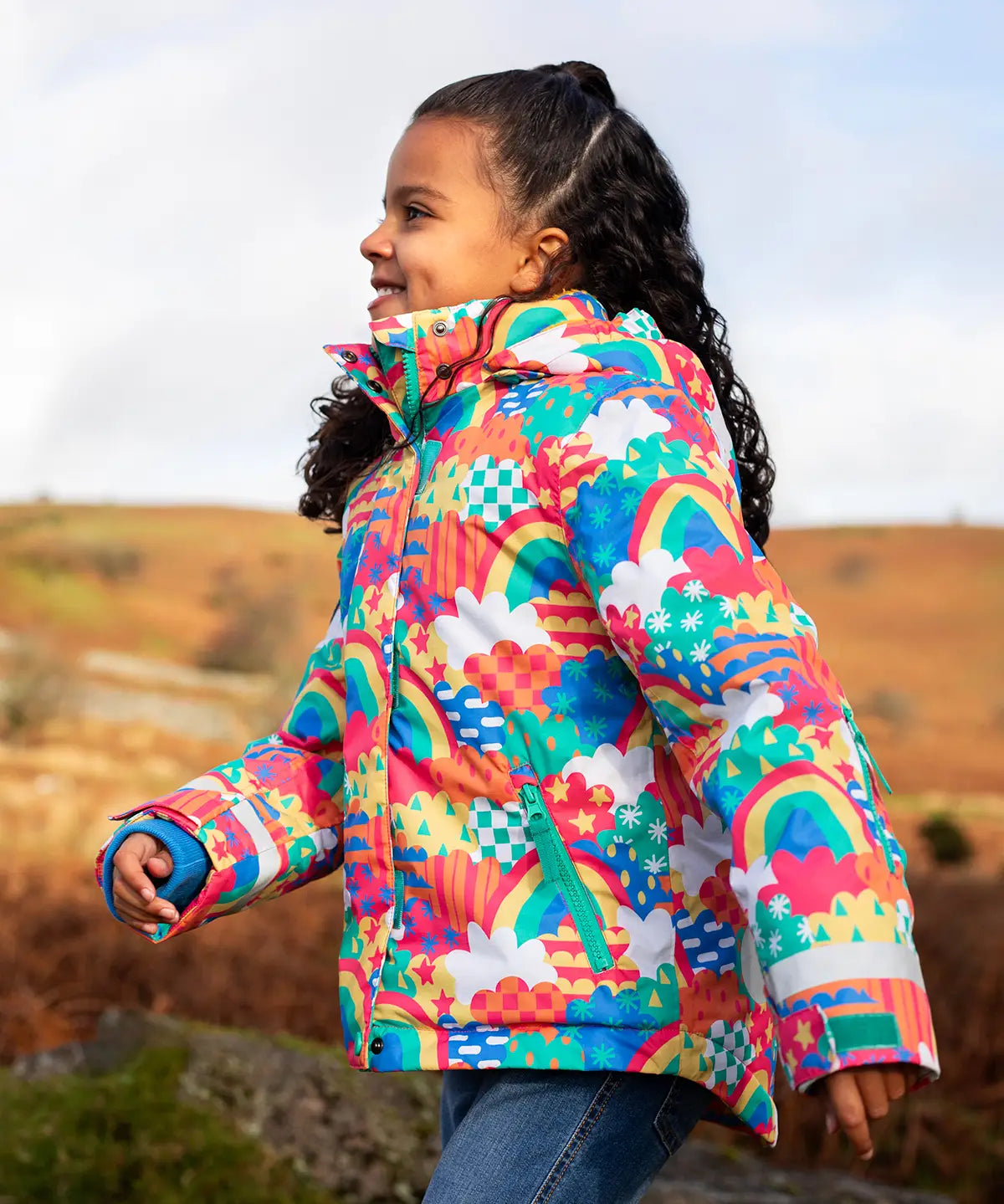 Child wearing the Frugi snow and ski coat in the fun frenzy design showing a zipped side pocket 