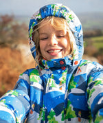 Child wearing the Frugi recycled polyester snow and ski coat in starry slopes with the hood up 
