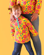 Child wearing Frugi's organic cotton snuggle fleece in yellow with repeating bright flower design prints.