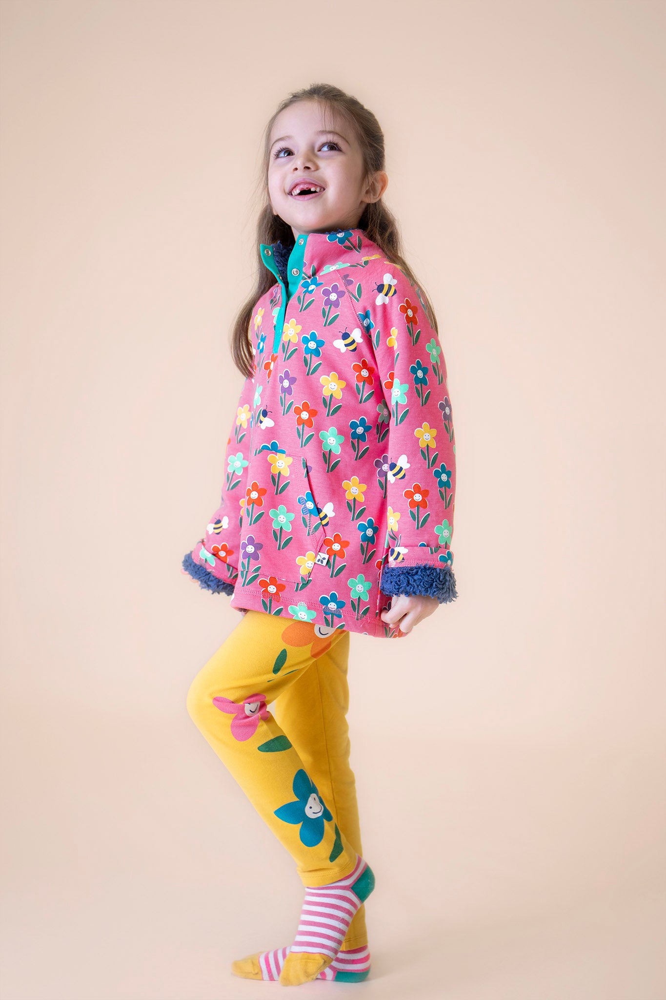 A child wearing the Frugi fun flowers snuggle fleece available at Babipur with the yellow Frugi fun flowers leggings