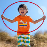 Child wearing Frugi's green and white striped shorts with repeating sun design  and a orange happy days applique tshirt