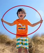Child wearing Frugi's green and white striped shorts with repeating sun design  and a orange happy days applique tshirt