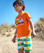 Child wearing Frugi's green and white striped shorts with repeating sun design  and a orange happy days applique tshirt