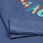 The navy sleeves on the Frugi Adventure Applique Top - Navy Blue/Magic, with some of the applique and embroidered letting showing partially under the folded sleeves