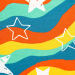 A closer up view of the Frugi Cosy Parsnip Pants - Wavy Stars/Protect Your Planet. The wavy star pattern has colours of red, yellow, green and blue, with white stars all over.