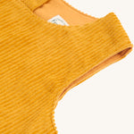 A closer look a the yellow, corduroy material and sleeveless shoulders on the Frugi Lovely Lily Cord Dress - Gold/Red Panda