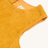 A closer look a the yellow, corduroy material and sleeveless shoulders on the Frugi Lovely Lily Cord Dress - Gold/Red Panda