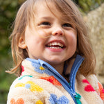 A child wearing the Frugi Zipped Ted Fleece Jacket - Flower Pop, showing the zipper open at the neck