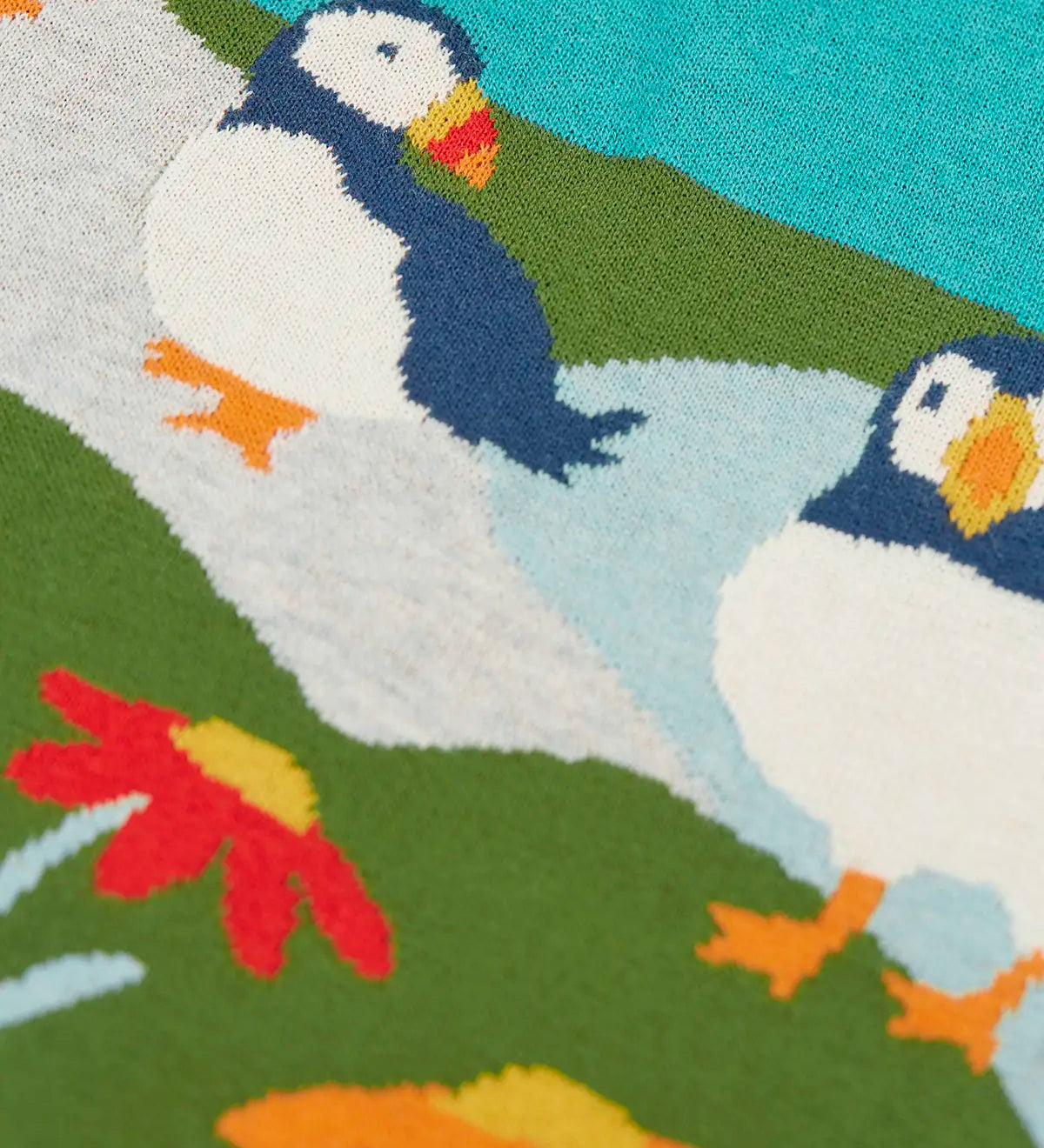 Frugi kids knitted dress showing a close up of the stitched puffins and flowers on organic cotton fabric