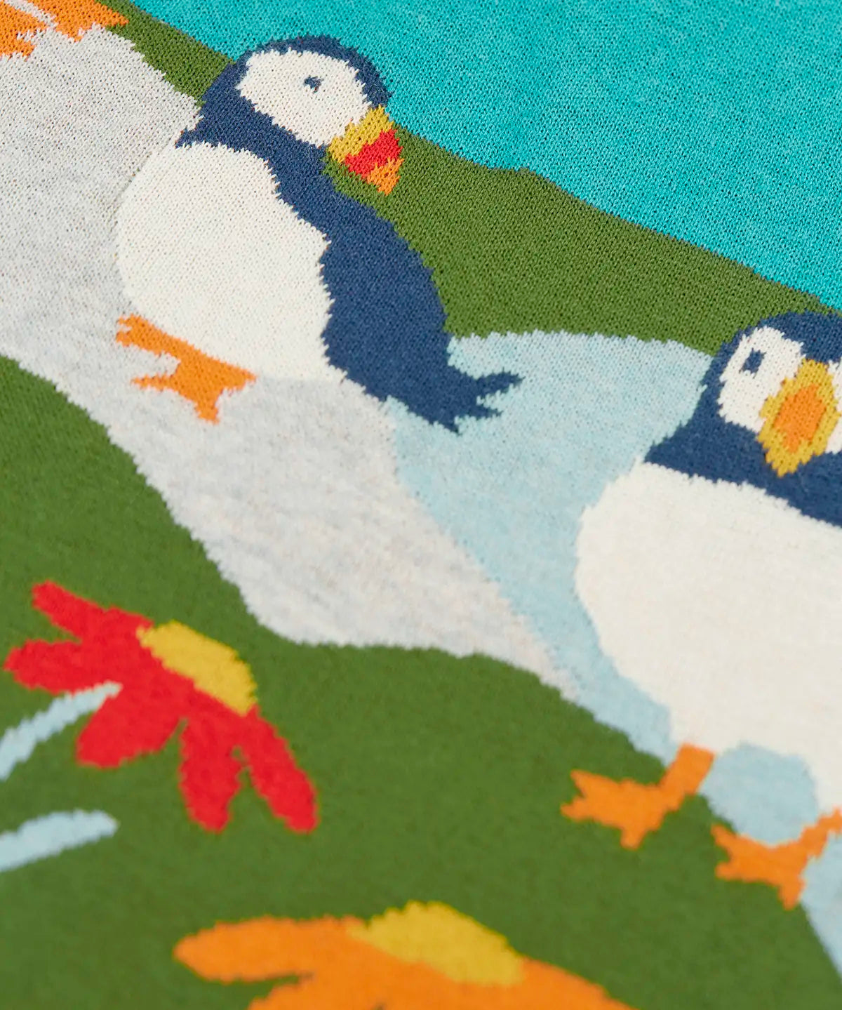 Frugi kids knitted dress showing a close up of the stitched puffins and flowers on organic cotton fabric