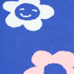 A closer look at the blue fabric and floral prints on the Frugi Zola Reversible Knitted Dress - Blue Tang/Retro Floral. The dress fabric looks very soft, and the flowers are white with a smily face, and a light baby pink