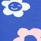 A closer look at the blue fabric and floral prints on the Frugi Zola Reversible Knitted Dress - Blue Tang/Retro Floral. The dress fabric looks very soft, and the flowers are white with a smily face, and a light baby pink