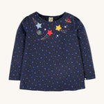 Frugi Laia Top - Starry Night/Space. A soft, organic cotton, navy blue, long sleeve top with light blue star pattern, with star and planet applique details around the neck collar