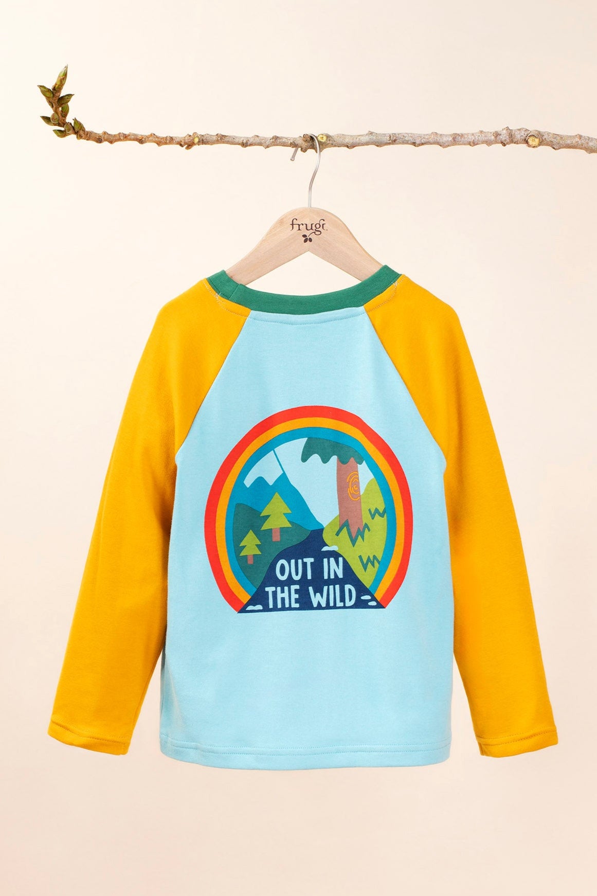 The back of the Frugi Children's Leo raglan long sleeved top hanging on a branch and available at Babipur.. The body of the top is light blue with yellow gold coloured sleeves and a contrasting dark green neck collar. The large circular graphic on the back features the words out in the wild written on a river surrounded by land, trees, mountains all surrounded by a three colour rainbow.