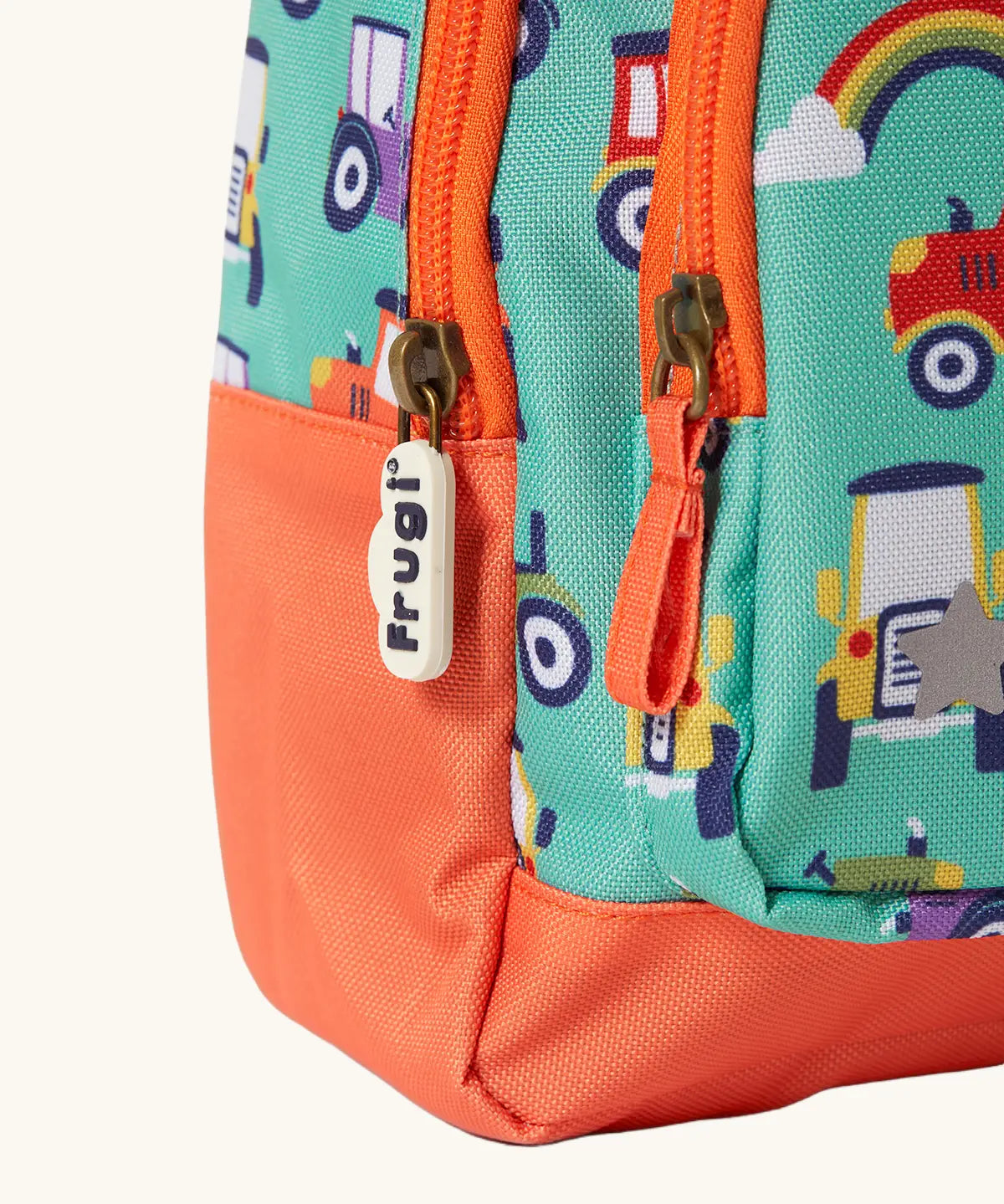 Frugi terrific tractors little adventures backpack showing a close up of the repeating tractor design and orange zip detail