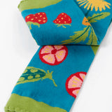 Frugi knitted leggings in light blue showing a close up of a repeating vegetables design on the leg and frilled green cuff on light blue organic cotton fabric