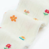 Frugi little pointelle kids tights in soft white showing a close up of a repeating floral and heart design on white organic cotton fabric