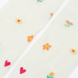 Pair of Frugi little pointelle kids tights in soft white laid flat showing a close up of the repeating floral and heart design on white organic cotton fabric