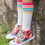 A child wearing Frugi trainers, and the Frugi Hygge Rib Knee Socks - Soft White Rainbow