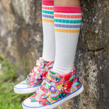 A child wearing Frugi trainers, and the Frugi Hygge Rib Knee Socks - Soft White Rainbow
