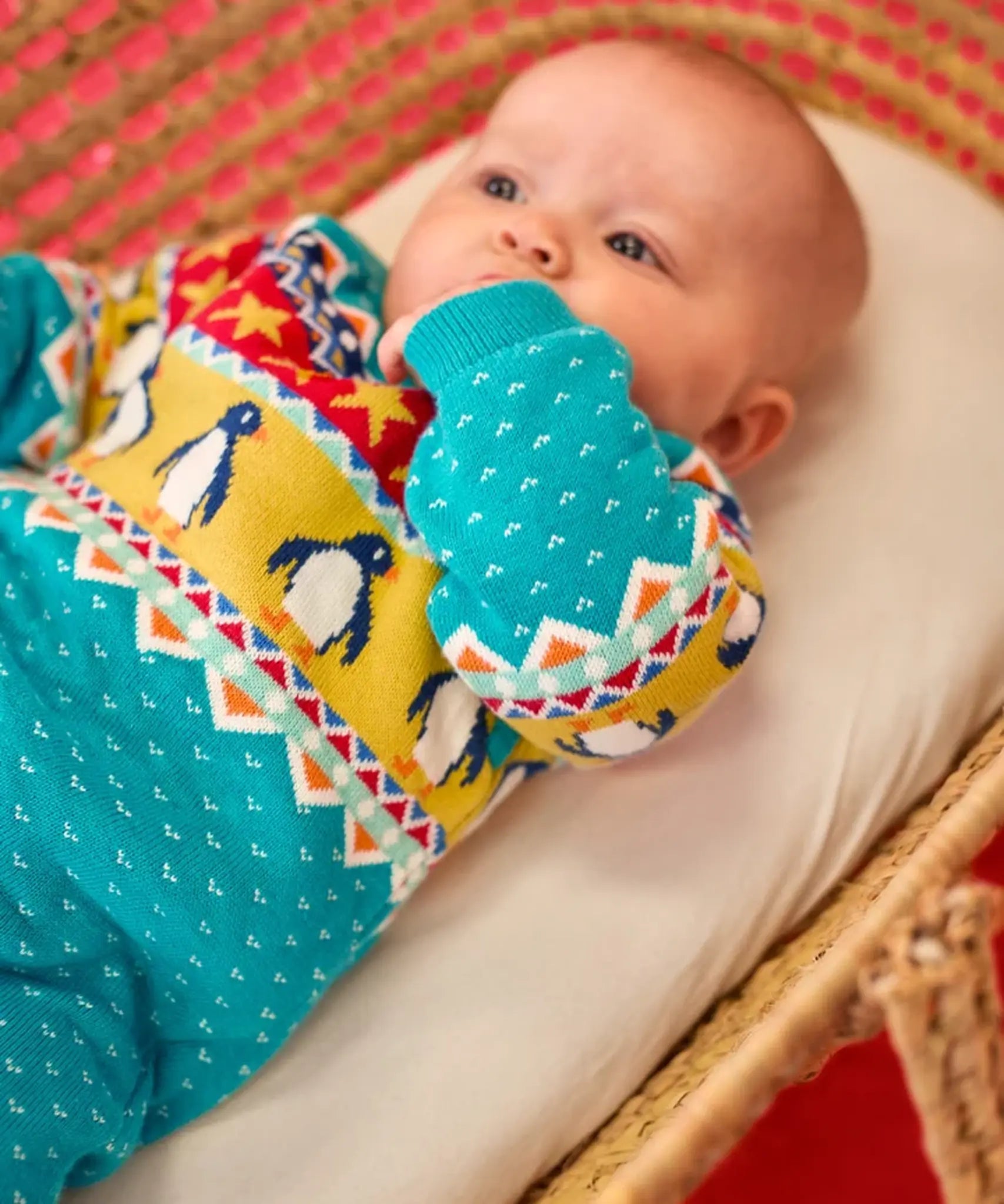 Baby wearing the Frugi GOTS 100% organic cotton knitted rompersuit in blue with a winter themed fairisle design on the upper half. Features elasticated cuffs and shoulder buttons for easy dressing.
