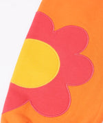 Frugi GOTS 100% organic cotton salamander orange organic joggers laid flat showing a close up pink flower applique on the lower leg