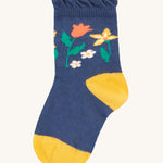 The navy blue socks from the Frugi Freya Frilled Socks 3 Pack - Rainforest Friends. This sock has a yellow toe and heel, with colourful flowers in a navy blue fabric