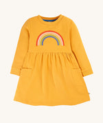 This beautiful long sleeve Niamh Dress from Frugi features a soft gathered waist and patch pockets. Made from super soft and durable organic cotton in Gold with a Rainbow embroidery detail on the front.