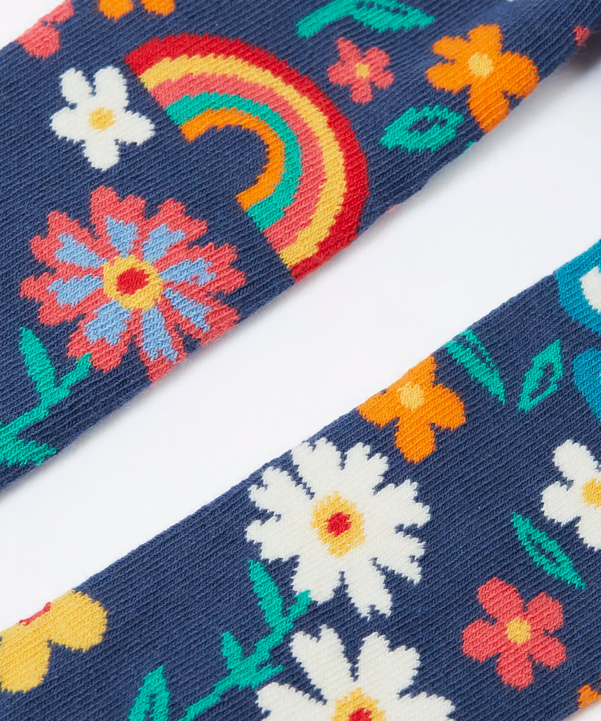 Pair of Frugi kids norah tights showing a close up of the playful floral design on  on navy organic cotton fabric