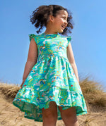 Child wearing Frugi's skater dress in aqua with a repeating seagull and mountain design on the beach 