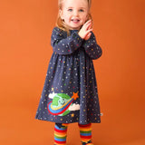 Frugi dolice dress in space and star design worn by little girl with rainbow tights.