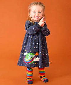Frugi dolice dress in space and star design worn by little girl with rainbow tights.