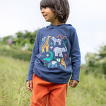 A child outside, wearing the Frugi Campfire Hooded Top - Navy Blue/Go Wild Animals and orange Frugi cord trousers