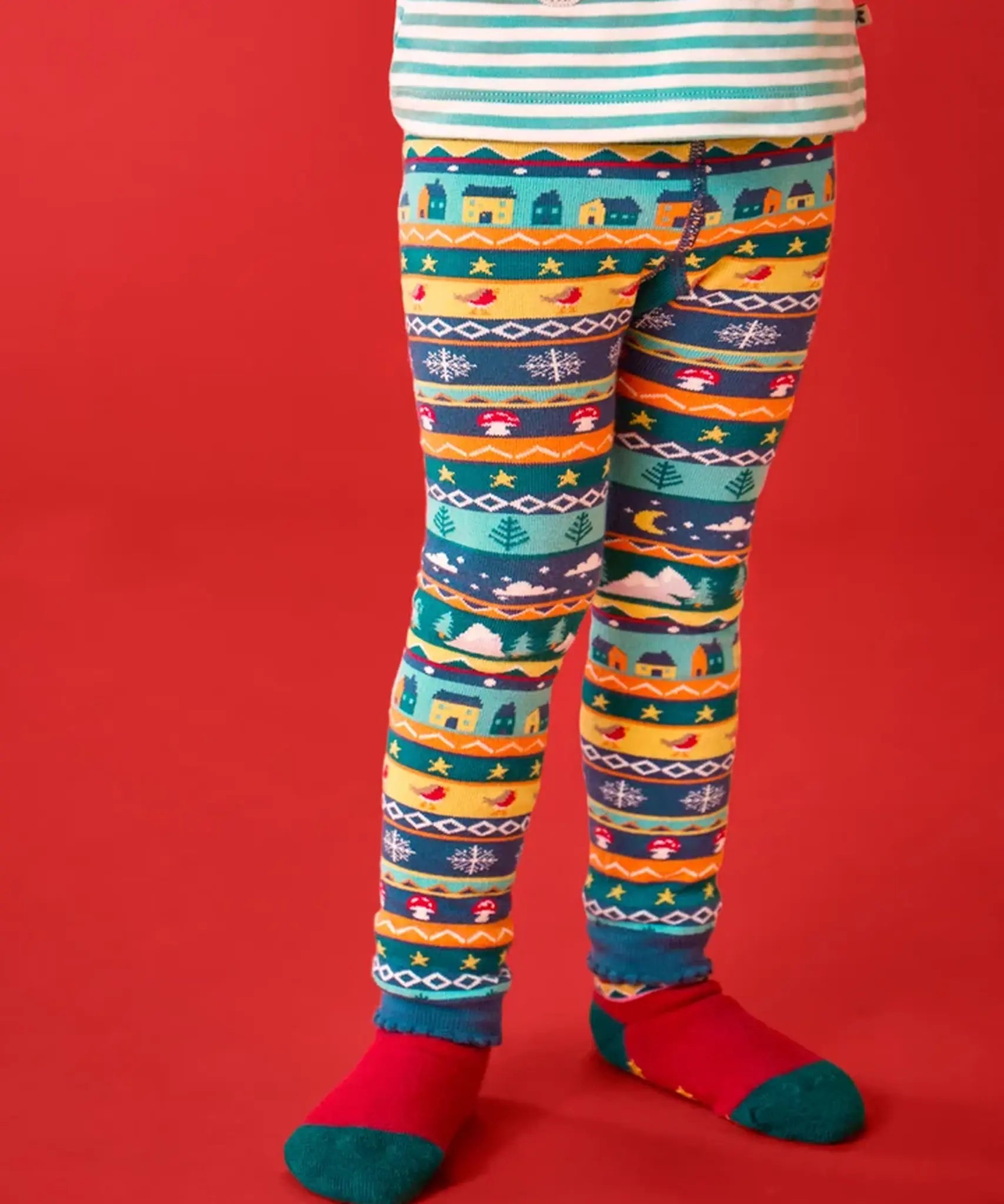 Child wearing the Frugi GOTS organic knitted footless leggings with a festive fair isle design with a Winter village design.