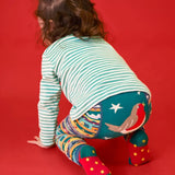 Child crawling away wearing the Frugi GOTS organic knitted footless leggings with a festive fair isle design with large robin on the back.