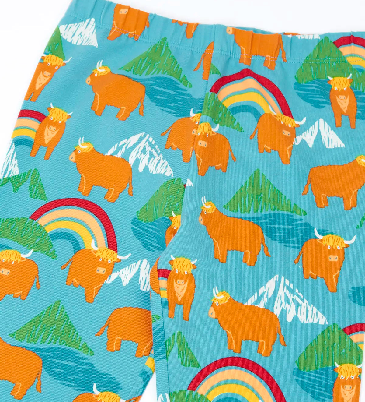 Frugi libby leggings in light blue with a repeating highland cow and mountain print showing a close up of the elasticated waist band