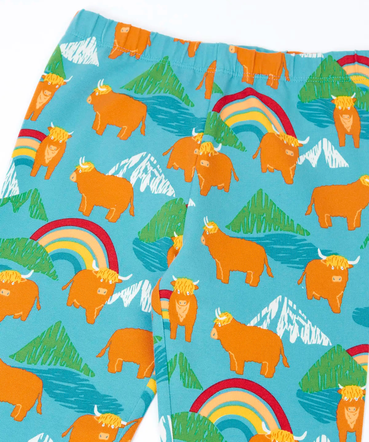 Frugi libby leggings in light blue with a repeating highland cow and mountain print showing a close up of the elasticated waist band