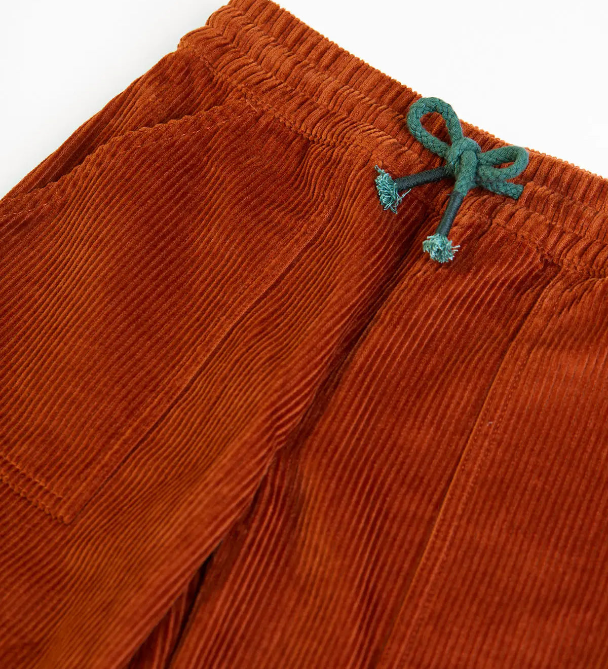 Frugi GOTS organic cotton children's corduroy trousers in rust brown laid flat showing a close up of the front pocket and green waist drawcord