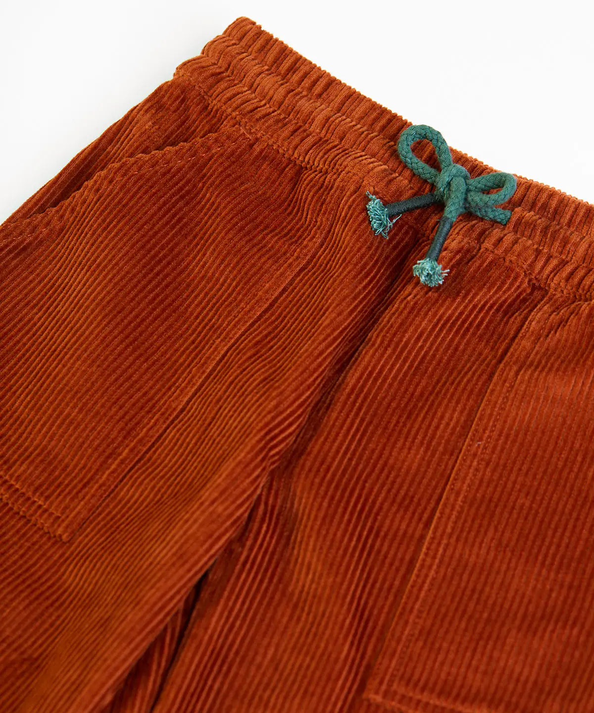 Frugi GOTS organic cotton children's corduroy trousers in rust brown laid flat showing a close up of the front pocket and green waist drawcord