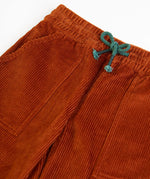 Frugi GOTS organic cotton children's corduroy trousers in rust brown laid flat showing a close up of the front pocket and green waist drawcord