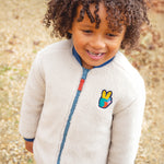 A chiled wearing the fleece side of the Frugi Robin Reversible Quilted Jacket - Teal/Moon