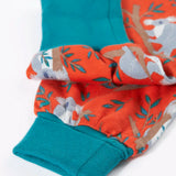 Frugi kids parsnip dungarees in salamander orange with repeating koala prints showing a close up of the fold up cuffs