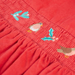 A closer look at the robin, holly leaf and mistletoe embroidery on the front of the Frugi Amilie Party Dress - True Red/Robin