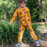 A child playing on tree stumps and wearing the Frugi beary wild parsnip joggers and matching sweater available at Babipur. 